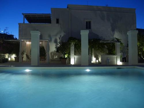 法萨诺Masseriola Antiche Fogge的一座大型游泳池,在晚上在房子前面