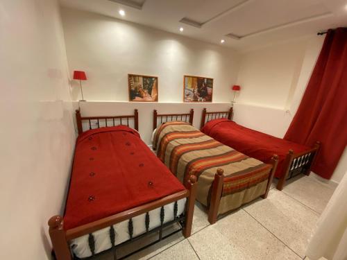 塔鲁丹特Appartement coeur de médina的小房间设有两张床,配有红色窗帘