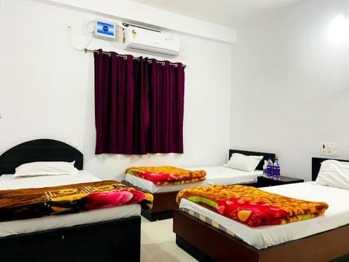 菩提伽耶Gaurav guest house的一间设有三张床和红色窗帘的房间