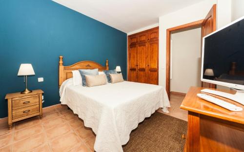 卡门港Luxury Diving Apartment的一间蓝色卧室,配有一张床和电视
