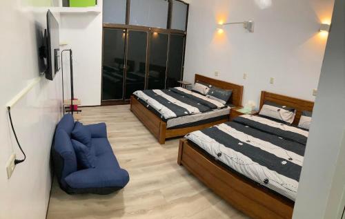 布袋瑞恒行館Reui Heng Guesthouse的一间卧室配有两张床和一张蓝色椅子