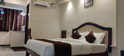 钦奈Rmc travellers inn的一间卧室配有带白色床单和棕色枕头的床。
