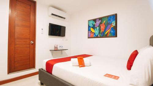 宿务RedDoorz Plus @ Costa Roca Balamban的酒店客房设有一张床,墙上挂有绘画作品