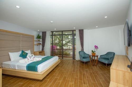 吉婆岛Emerald Hotel Cát Bà的一间卧室配有一张床、一台电视和一把椅子