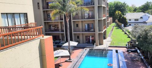 约翰内斯堡St Andrews Hotel and Spa的公寓大楼设有游泳池和棕榈树