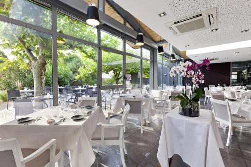Saint-Germain-lès-Arlay圣日耳曼客栈的餐厅设有白色的桌椅和窗户。