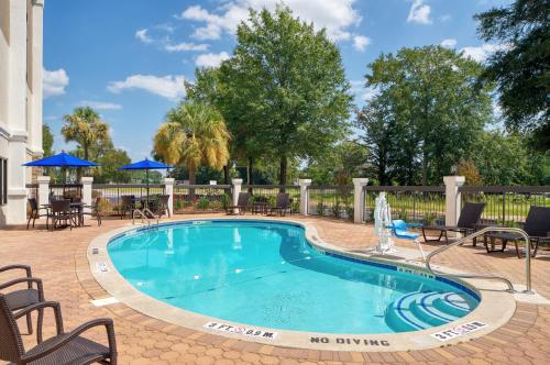 斯泰茨伯勒Holiday Inn Express Statesboro, an IHG Hotel的一个带桌椅的游泳池和一个围栏