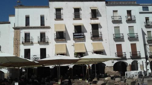 卡塞雷斯Pension Carretero的前面有桌子和伞的建筑