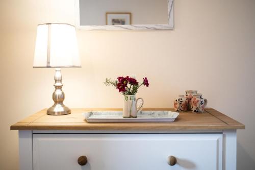 福里斯Mill Cottage的一张桌子,上面有台灯和花瓶