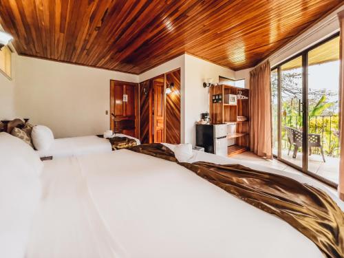 福尔图纳Miradas Arenal Hotel & Hotsprings的一间卧室设有一张大床和一个大窗户