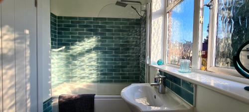 雷利Station Heights的一间带水槽和绿色瓷砖墙的浴室