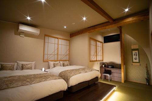 名古屋Ixyz別邸 月夜見の宿的一间卧室配有两张床和电视。