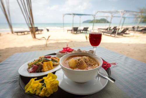 麦岛Sabai Beach Resort的一张桌子,上面放着一碗汤和一杯葡萄酒