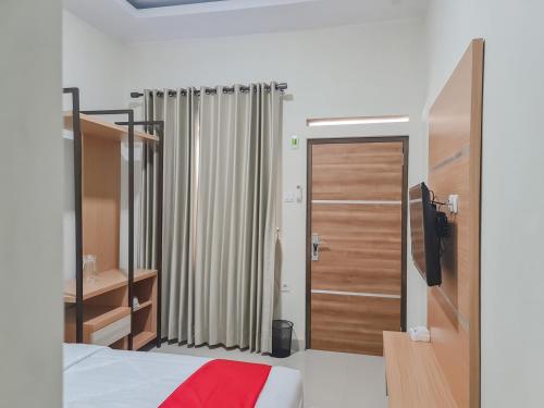 打横RedDoorz Syariah @ Boemi Guesthouse Tasikmalaya的一间卧室设有一张床和一个推拉门