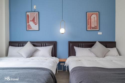 台东H& Taitung Feng Lin Resort Hotel的蓝色墙壁客房的两张床