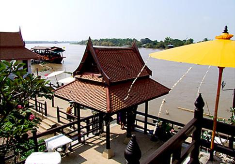 Ban Bang Krasan大城府河畔景苑酒店的水边有黄色雨伞的建筑