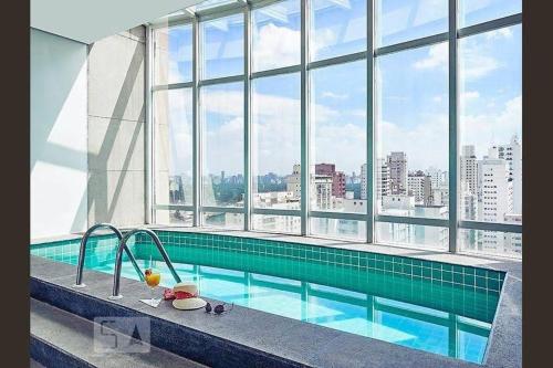 圣保罗Ótimo flat Jardins SP entre Av. Paulista e Pq. Ibirapuera.的一座带大窗户的建筑中的游泳池