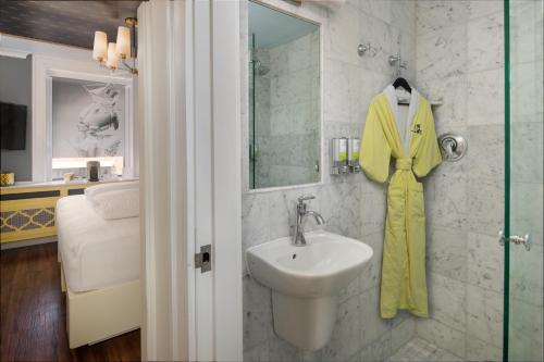 波士顿Staypineapple, A Delightful Hotel, South End的浴室设有水槽,墙上有黄色的浴袍。