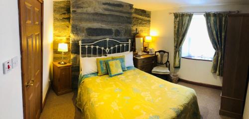 波特马多克Yr Hen Fecws的一间卧室设有一张黄色的床和石墙