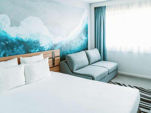 安格雷诺富特安格雷比亚里茨Spa度假酒店的配有一张床和一把椅子的酒店客房