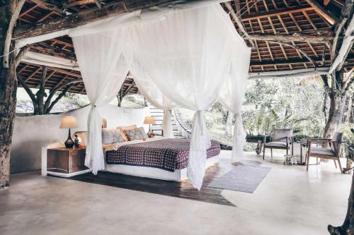 塔巴南Batukaru Coffee Estate的一间卧室配有天蓬床和桌椅