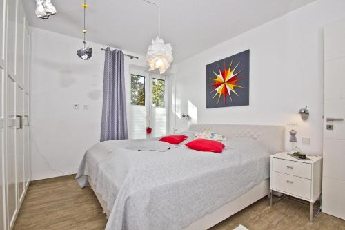 劳特尔巴赫hafennahe Ferienwohnung im Erdgeschoss mit Terrasse - Haus Hafenkieker FeWo 02的白色卧室配有白色的床和红色枕头