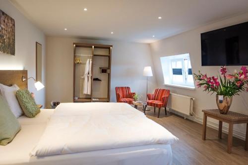 芬洛瓦鲁亚斯酒店的一间卧室配有白色的床和两张红色椅子