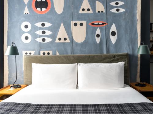 纽约纽约王牌酒店的一张带白色枕头的床和一堵眼睛的墙