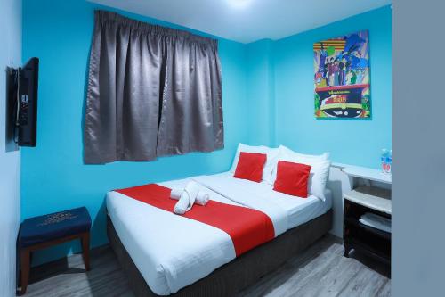 汝来Hotel Aman- Nilai & KLIA的一间卧室配有一张带红色枕头和蓝色墙壁的床。