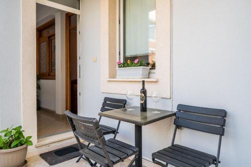 杜布罗夫尼克Apartment Jelena的庭院里的桌椅和一瓶葡萄酒