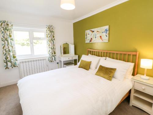 莱伯恩Daisy Cottage的卧室配有白色的床和电视。