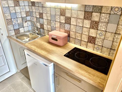 希欧福克Aqua Blue Apartmanok - Siófok的厨房柜台设有水槽和粉红色的盒子