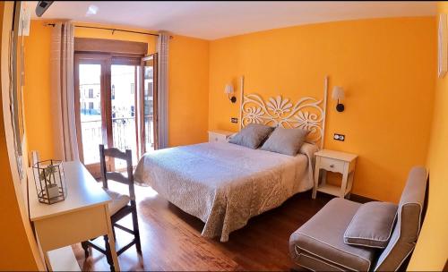 卡里翁德洛斯孔德斯Hostal Plaza Mayor的黄色客房内的一间卧室配有一张大床