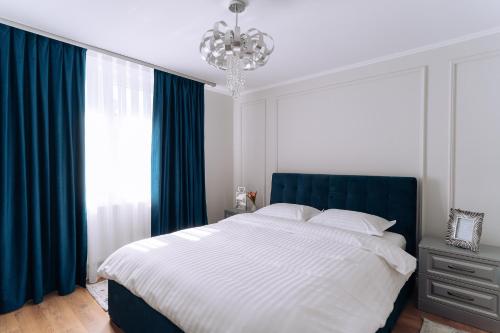 奥拉迪亚GOLD Suites的一间卧室配有一张带蓝色窗帘和吊灯的床。