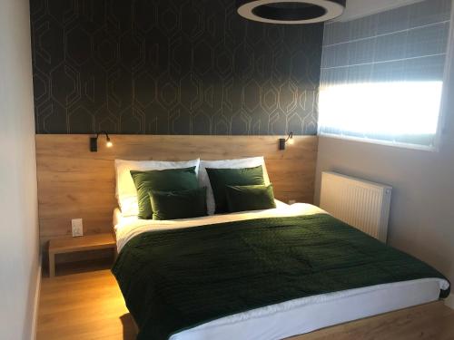 什切尔克Plażowa Residence的一间卧室配有一张带绿色枕头的大床