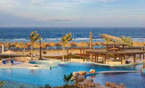 库塞尔Lazuli Hotel, Marsa Alam的一个带两个游泳池和遮阳伞的度假胜地,以及大海