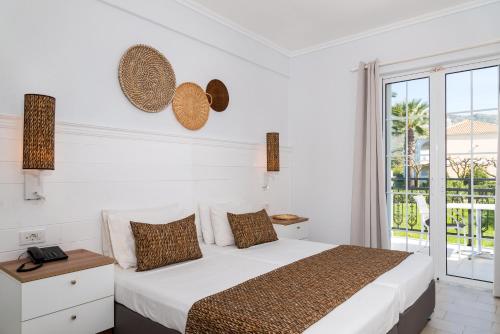 扎金索斯镇Sirocco Hotel的白色的卧室设有床和大窗户
