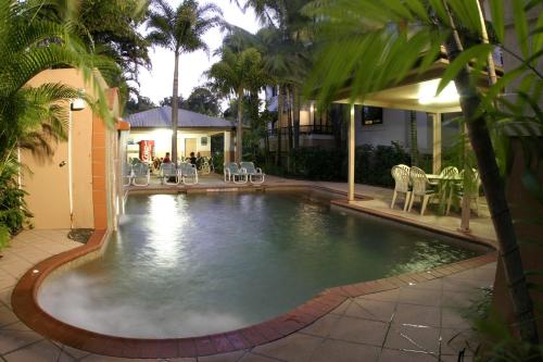 凯恩斯凯恩斯格罗夫纳酒店的庭院内的游泳池,配有桌椅