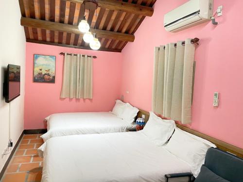 金城心琴民宿-市区馆的配有粉红色墙壁的客房内的两张床