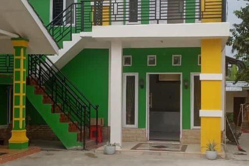 RantauprapatGreen House Syariah Mitra RedDoorz的绿色的建筑,设有楼梯和门