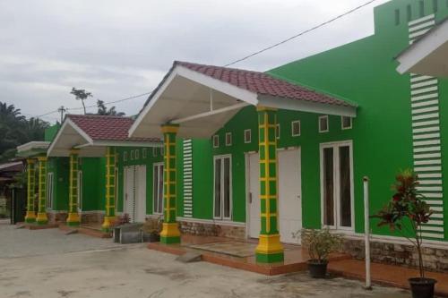 RantauprapatGreen House Syariah Mitra RedDoorz的绿色和白色的房屋,有黄色的柱子