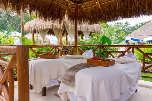 坎昆Tsaakik Jungle Hotel & Spa的度假村内2张稻草伞下的床铺