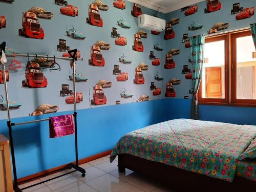 日惹拉巴尼家庭度假屋的卧室设有蓝色墙壁,墙上挂有汽车