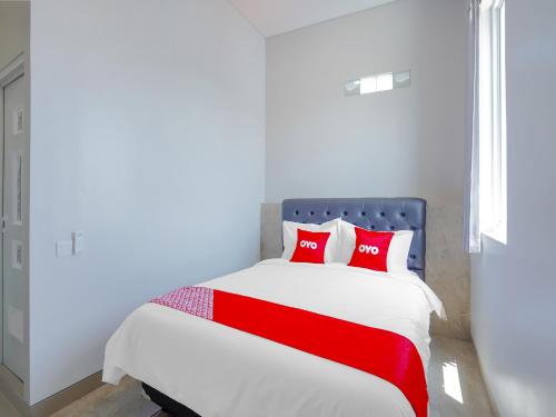 泗水Super OYO Capital O 90336 Olive Guest House的一间卧室配有红色枕头的床