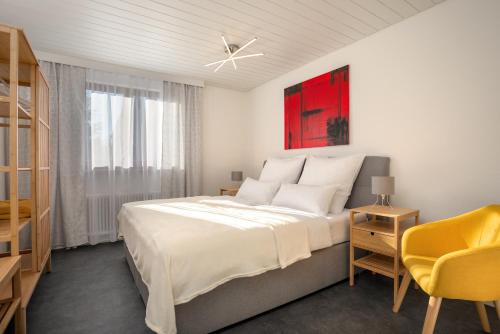 纽伦堡Ferienhaus Villa Milla Nürnberg的白色卧室设有一张大床和一张黄色椅子