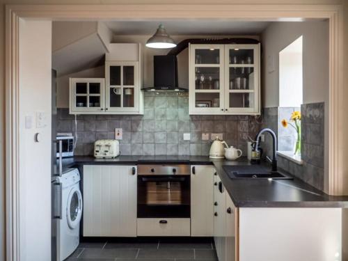 克利夫登Rosies的厨房配有白色橱柜、水槽和洗碗机。