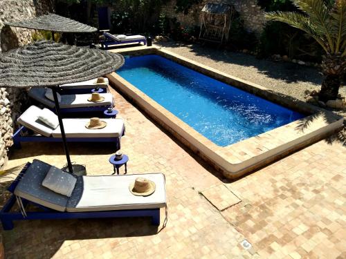 GhazouaDar Mayssoun的一个带2把躺椅和遮阳伞的游泳池