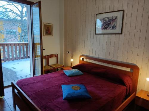 蒙泰克雷托Bilocale Gran Chalet Montecreto的一间卧室配有一张带紫色毯子的床和一个阳台