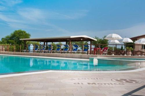 里沃托托卡萨莱莫妮卡2号庄园酒店的度假村的游泳池,配有椅子和遮阳伞