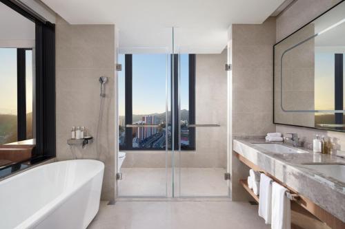 承德承德元宝山假日酒店的带浴缸、两个盥洗盆和淋浴的浴室。